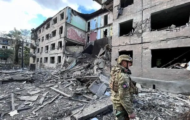 Військовий стоїть серед уламків біля зруйнованої обстрілом багатоповерхівки з вигорілими вікнами — наслідки ударів…