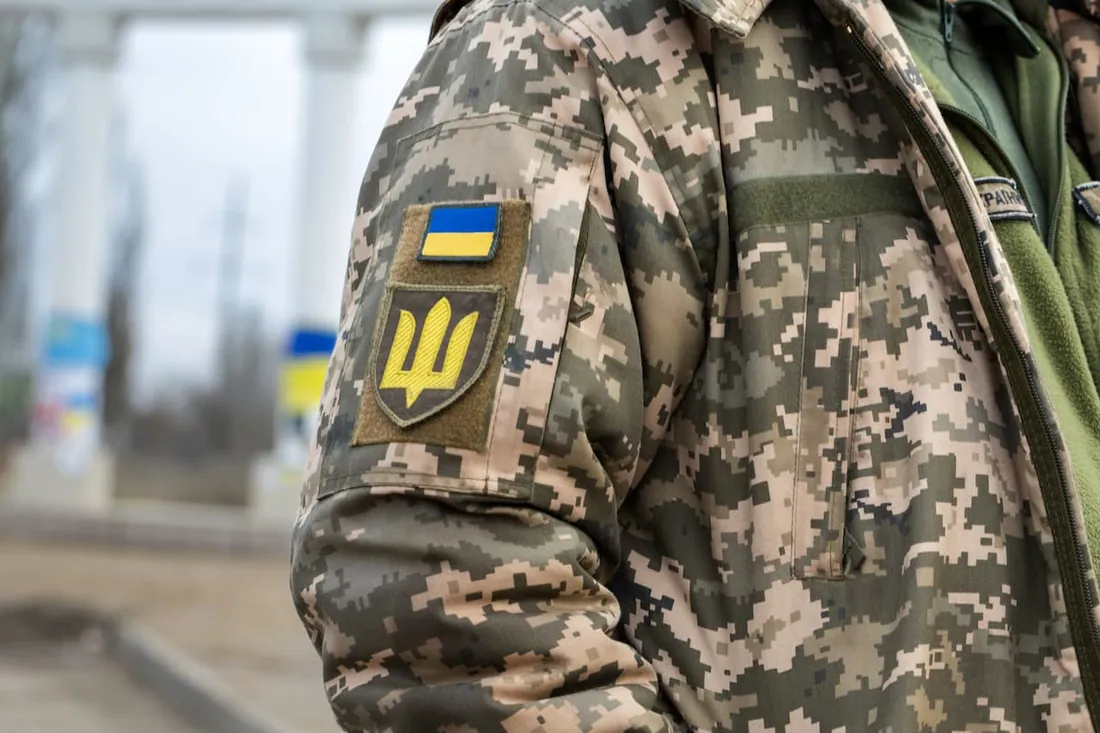 Крупний план рукава піксельної форми з шевроном прапора України та емблемою Збройних Сил (тризуб-меч) — сектор безпеки та оборони.