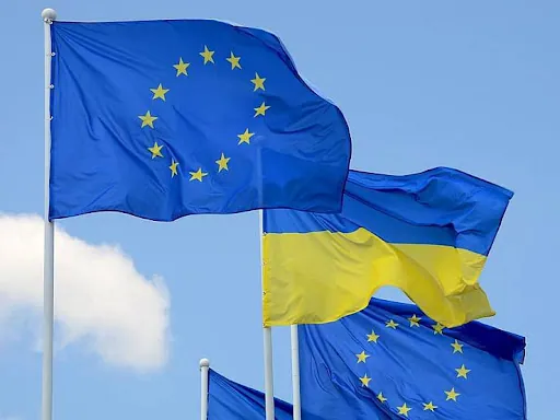 Прапори Європейського Союзу та України на флагштоках на тлі неба — європейська інтеграція, міжнародні зобов'язання.
