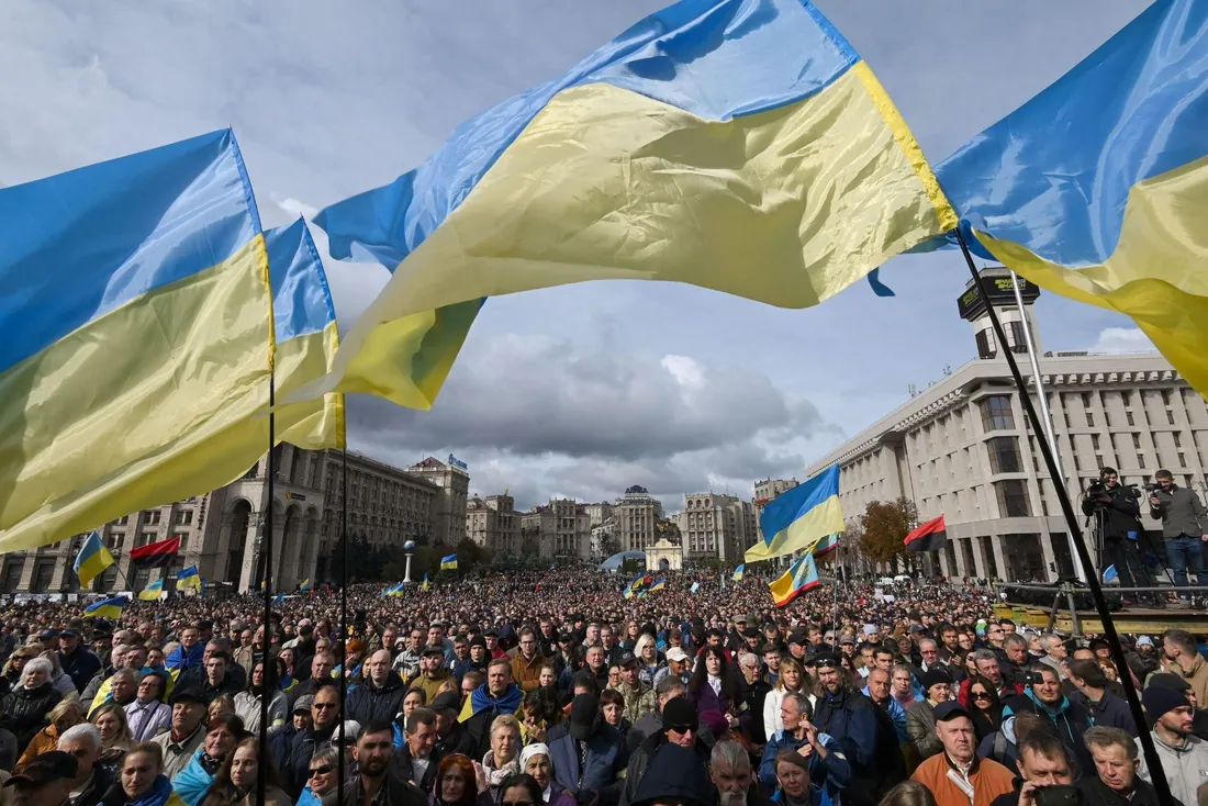Майдан Незалежності в Києві: багатотисячний натовп, над ним великі прапори України, видно Головпоштамт і Будинок…