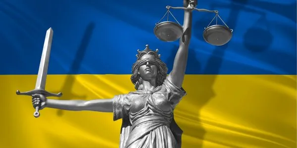 Статуя Феміди з мечем і терезами на тлі прапора України — правосуддя, конституційний обов'язок і закон.