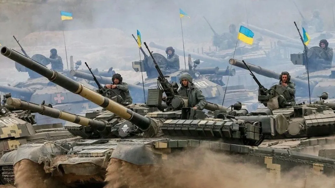 Колона танків Т-72/Т-64 із піднятими прапорами України рухається запиленою місцевістю, на броні екіпажі — Сили оборони…