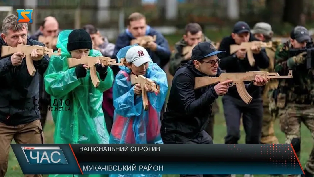 Цивільні різного віку в дощовиках відпрацьовують прицілювання з макетами автоматів під наглядом інструкторів; титр…