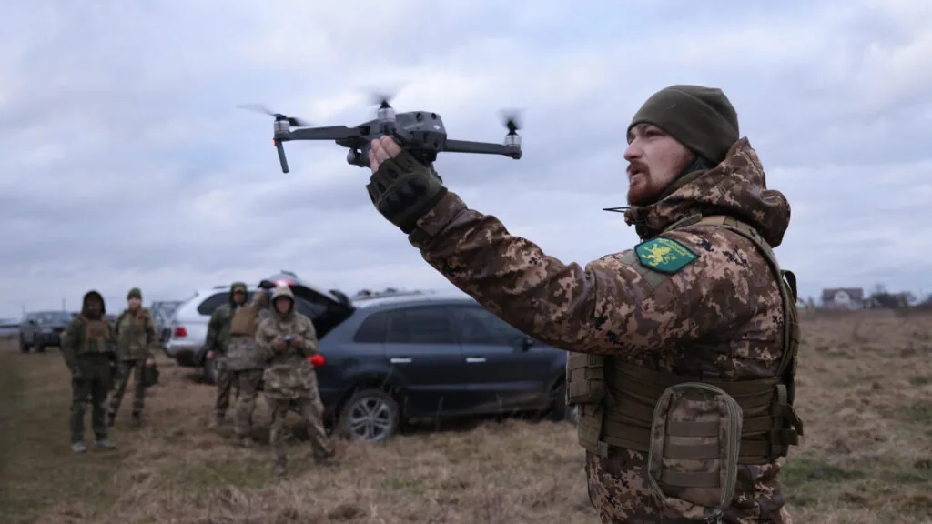 Військовий у полі запускає з руки квадрокоптер DJI Mavic; позаду група бійців і автомобілі — напівавтономні системи…
