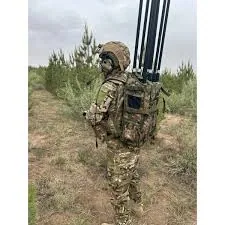 Боєць у полі несе на спині ранцеву станцію РЕБ із кількома вертикальними антенами — війська радіоелектронної боротьби.