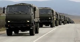 Колона військових вантажівок КамАЗ рухається шосе одна за одною — автомобільні війська, підвезення матеріальних засобів.