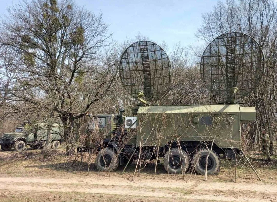 Тропосферна станція на шасі вантажівки з двома великими сітчастими антенами-рефлекторами, замаскована серед дерев — тропосферний зв'язок.