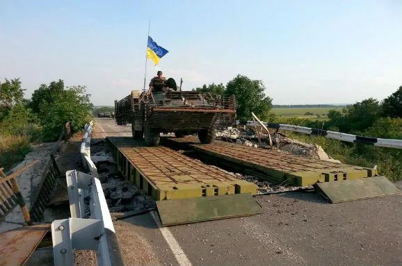 БМП із прапором України переїжджає через понтонно-мостову переправу, наведену інженерами на місці зруйнованого мосту…