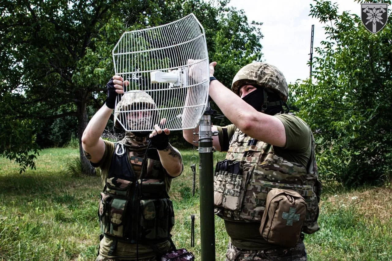 Двоє військових встановлюють на щоглу сітчасту параболічну антену радіорелейного/Wi-Fi каналу — розгортання вузла…